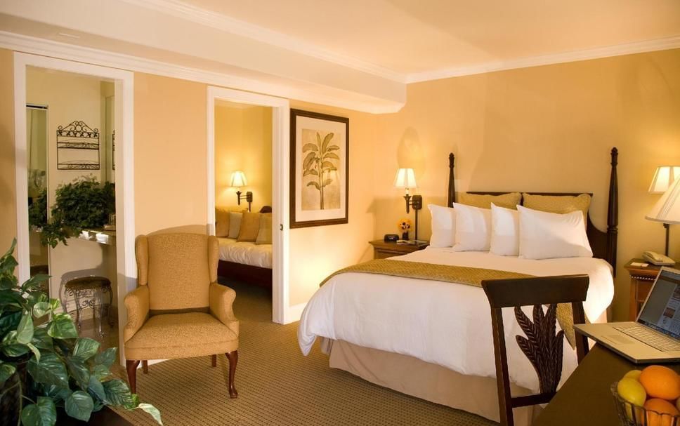 A hotel room with a large bed, chair, desk, and lamp.
